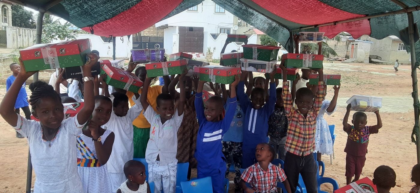 Children holding up gift boxes during a community outreach event
